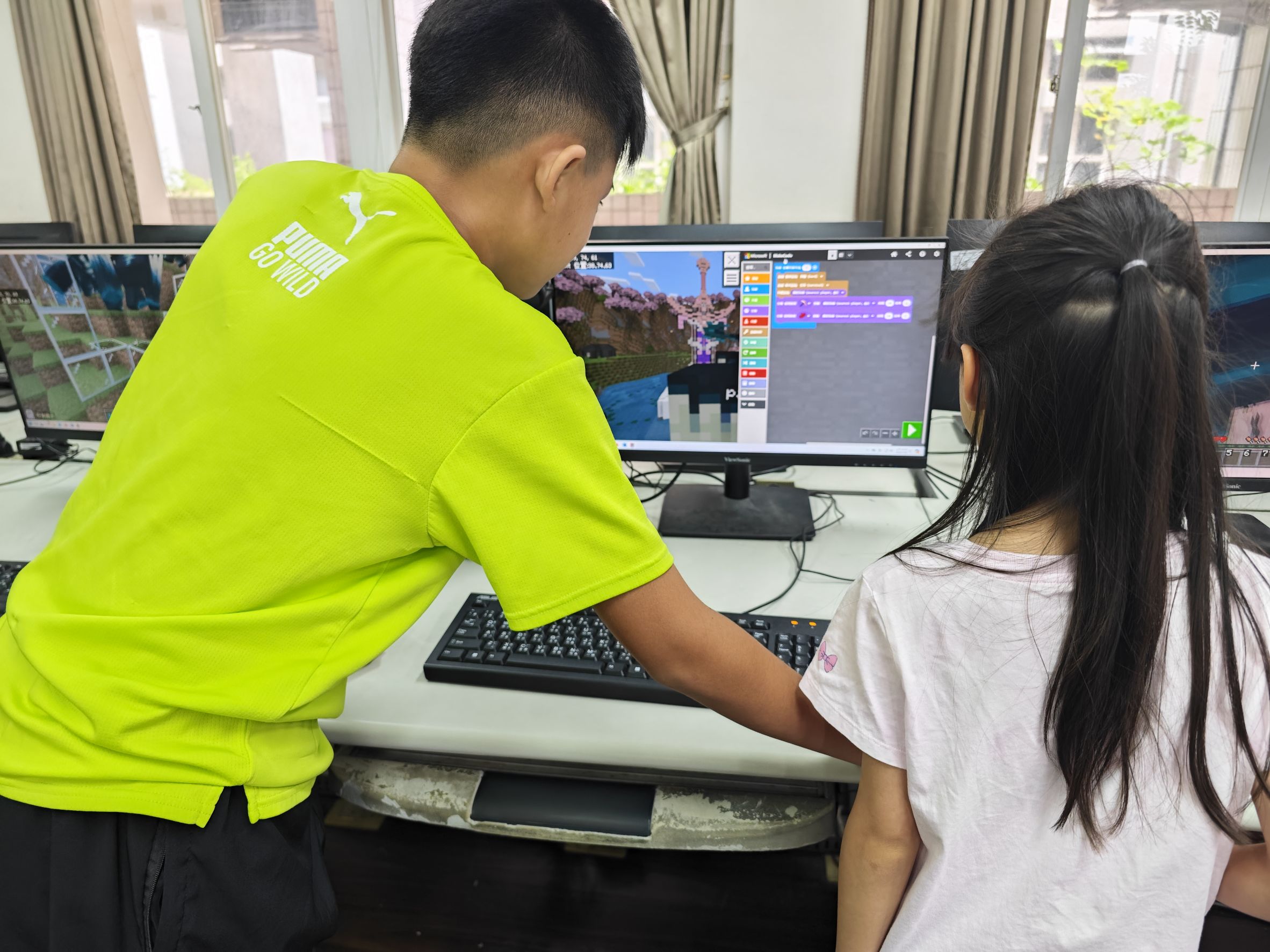 星圖創學程式營隊學員共同在電腦螢幕前討論程式碼與進行 Debug 除錯,培養軟體工程師解決問題的韌性與協作精神